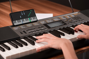 Boy playing piano and using an app on his phone to learn © yuriygolub