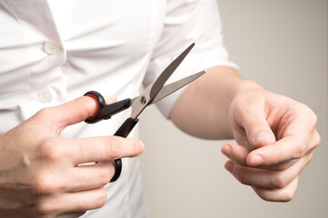 A woman in a white shirt is going to cut hair, scissors in her hands on a beige background.