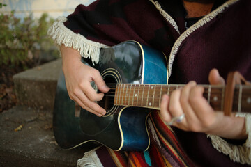 Musician Playing the Guitar - Hipster Man in a Poncho playing a blue guitar