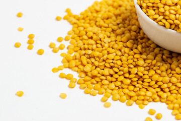 Yellow lentils in a white bowl on a white background