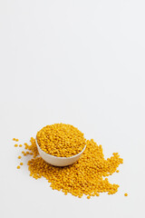 Yellow lentils in a white bowl on a white background