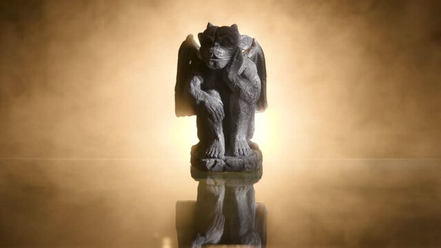 A creepy little gothic gargoyle backlit with flickering light and eerie fog.