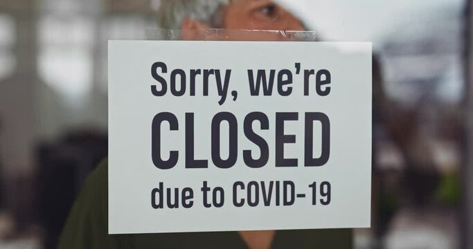 Woman closing business due to covid-19 pandemic outbreak with sign