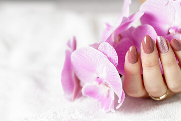 Beautiful hands with fresh manicure and orchid flower