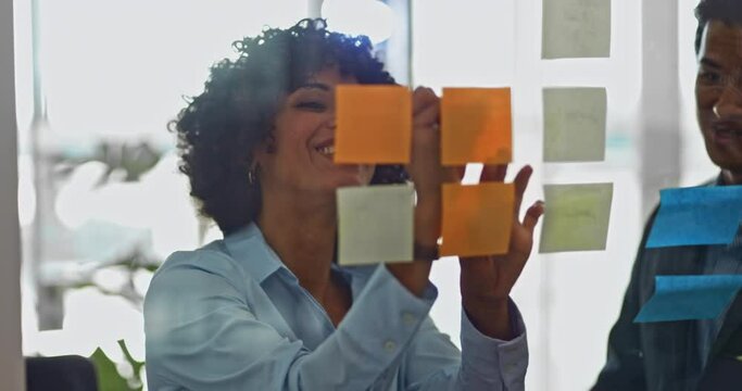 Business woman and colleague writing on sticky notes in office