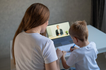 A boy learns the alphabet with a laptop teacher. Distance learning by video conference. Remote preschool education.