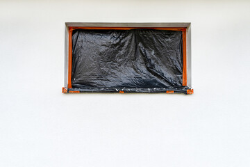 A newly applied layer of white silicone plaster on the wall of the house, the window is secured...