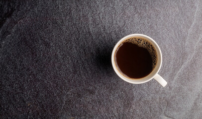 Top view a cup of coffee  on the black stone.
