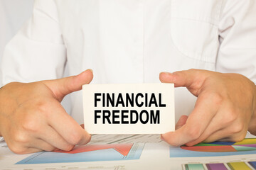 the man's hands hold a business card with text FINANCIAL FREEDOM. business concept. business and Finance