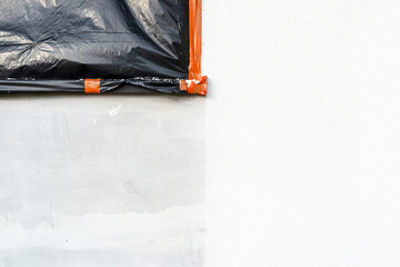 A newly applied layer of white silicone plaster on the wall of the house, the window is secured...