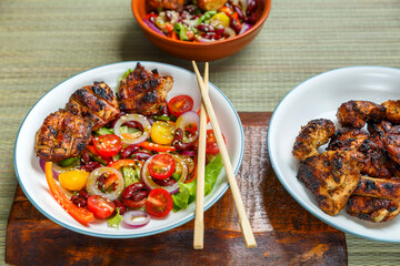 Plates of Pan-Asian sesame and tamarind salad and grilled chicken pieces in pad thai sauce.