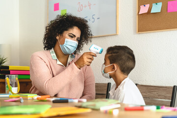 Teacher woman checkup temperature on child in classroom during corona virus pandemic - Healthcare medical and education concept - obrazy, fototapety, plakaty