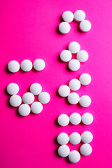 COVID 19 lettering made of white medical pills on a bright pink background