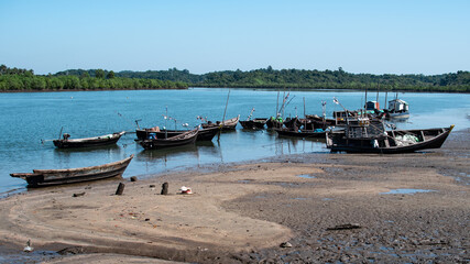 Fototapeta na wymiar Wooden fishing boats by the river during low tide, Chaung Thar, Myanmar