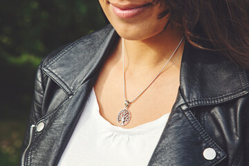 Female neckline wearing tiny silver chain with silver pendant in the shape of tree in mandala