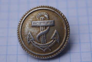 old aluminum german military button with sea anchor lies on white paper