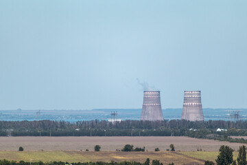 Zaporizhzhia Nuclear Power Plant two big cooling factory pipes at a distance. Industrial smoke in...