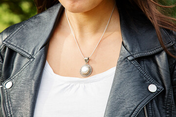 Female neckline wearing tiny silver chain with silver pendant with white pearl