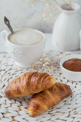 Delicious breakfast with fresh croissants and cup of coffee served with jam on a white wooden background. Delicious Baking