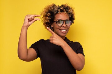 Glad beautiful african woman shows something small with hands