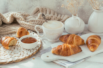 Delicious breakfast with fresh croissants and cup of coffee served with jam on a white wooden background. Delicious Baking