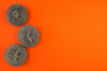 Top view on a bright orange background metal scouring pads for cleaning dishes and pans. Kitchen...