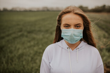 Young blond European woman in a protective mask outdoors.