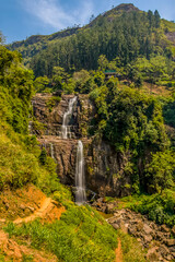 Fototapeta na wymiar A long exposure shot of water cascading over two vertical cliff faces at Ramboda Falls in upland tea country in Sri Lanka, Asia