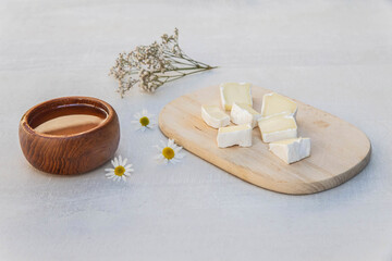 Obraz na płótnie Canvas Blue cheese on a wooden plank, honey and flowers