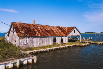 Fototapeta na wymiar This is a view of an abandoned oyster house along the shores of Chincoteague Bay on George Island Landing, a declined oyster, clam, and crab fishing village in Maryland.