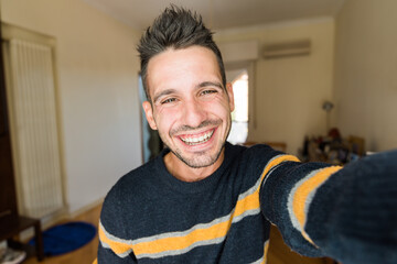 Handsome caucasian man taking a selfie portrait indoor at home - Happy guy smiling at the camera.