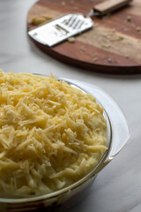 uncooked cottage pie with grated cheddar cheese topping 