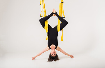 sportswoman hanging in a hammock in an inverted position on a white background