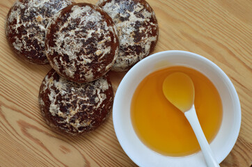 Honey in a white cup and chocolate gingerbread on a wooden background