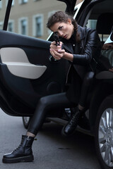 A girl in the driver's seat of a car with a gun in her hands