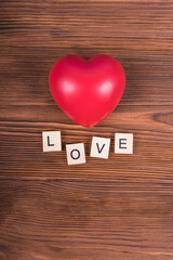 Red heart with the text love on a wooden background. Postcard or wallpaper with congratulations on valentine's day, recognition of feelings, valentine.