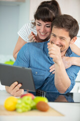 portrait of a smiling young couple cooking with tablet