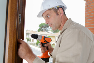 mid-adult man drilling hole in wall