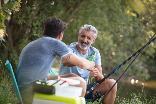 Two Male Friends Having A Beer While Fishing