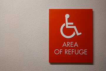 A sign in a hallway in an apartment complex that says Area of Refuge with a wheelchair symbo