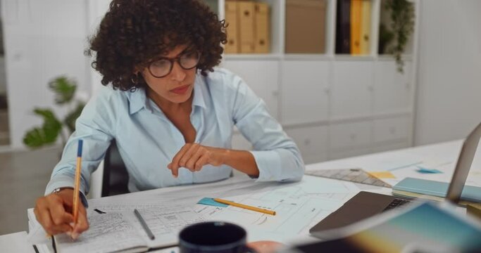Female architect working on laptop and writing notes of floorplans