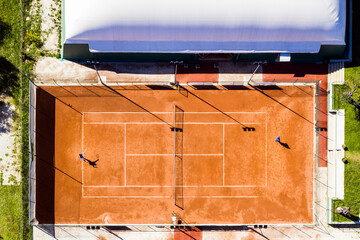 View from above, aerial view of two people playing tennis on a clay court during the Coronavirus...