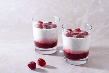 Glass glasses with fresh natural homemade organic yogurt with natural raspberries and chia seeds on a light background.