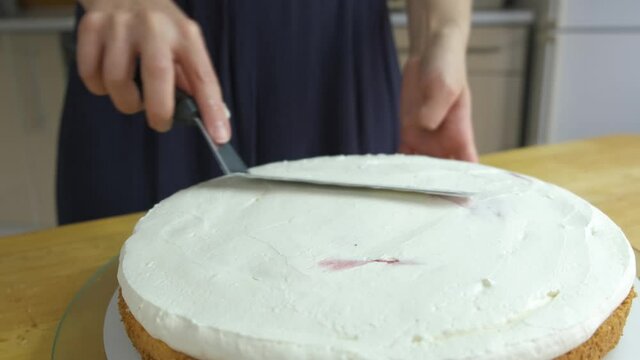 Close up of woman hands making sweet cake with white cream and biscuit.