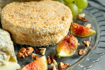 Camembert with grapes, walnuts and figs close-up on the gray background