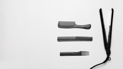 Black hair iron and hairbrush on white background with copy space