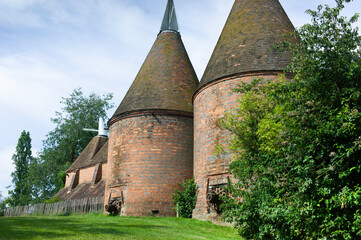 Oast house building designed for kilning (drying) hops as part of the brewing process. Blue sky,...