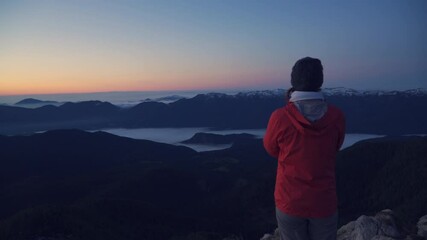 Wide angle, Female hiker admire beautiful view at the top of the mountain at sunrise. Magical light and scenery.