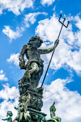 Fototapeta na wymiar The statue of Neptune with trident on a blue sky with white clouds background in Tubingen, Germany, reconstruction by David Fahrner of the 1617 fountain