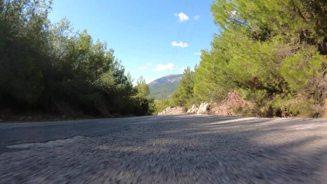 Time Lapse video of forest curvy road taken by stabilised camera attached to motorcycle as seen from lowest possible asphalt perspective 
